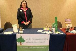 Denise W. Grove of Grove Solutions Standing behind a booth at convention